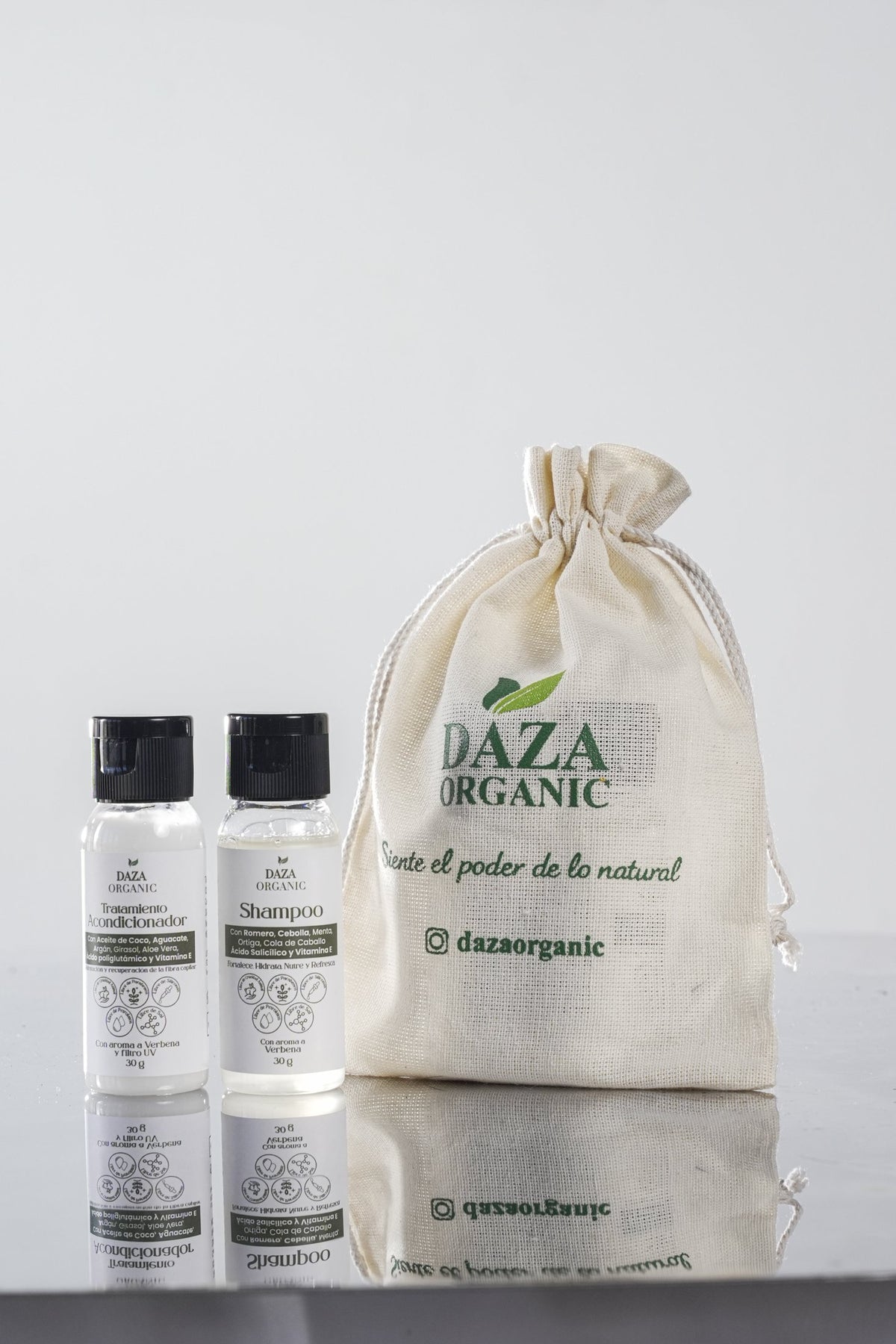 Kit de viaje de Daza Organic: el shampoo y el tratamiento acondicionador en frascos pequeños junto a una bolsa de tela con el logo y la frase «Siente el poder de lo natural».